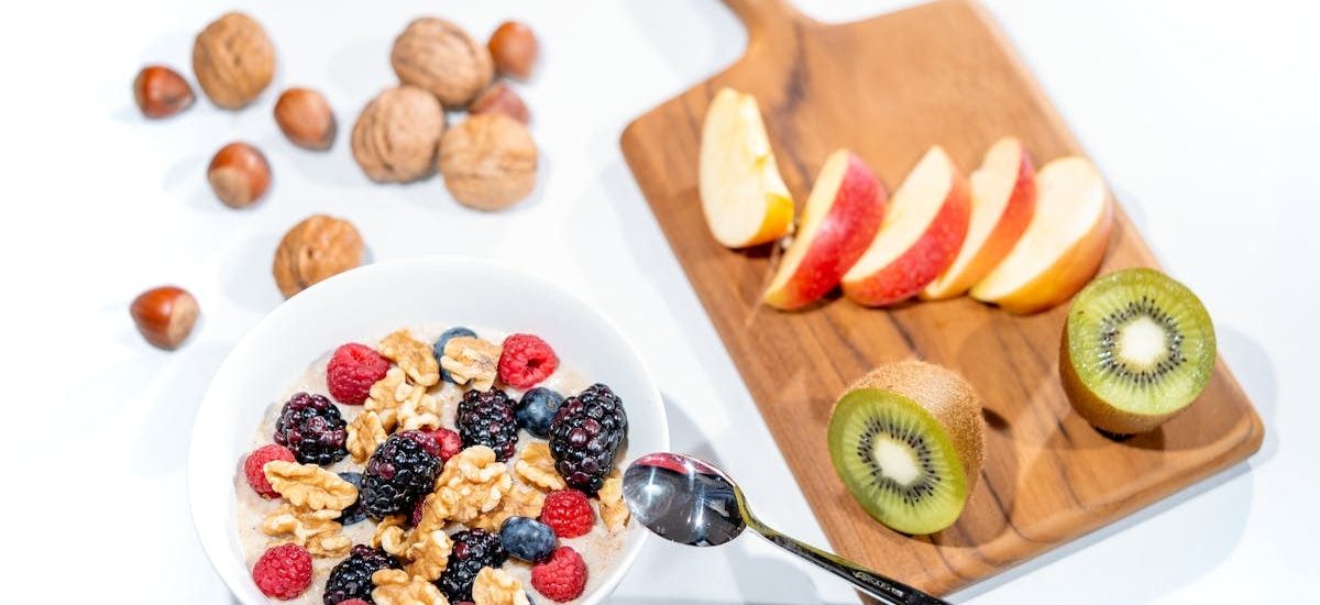 A nutritious breakfast bowl featuring fresh berries and walnuts, served with sliced fruit and kiwi.