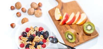 A nutritious breakfast bowl featuring fresh berries and walnuts, served with sliced fruit and kiwi.